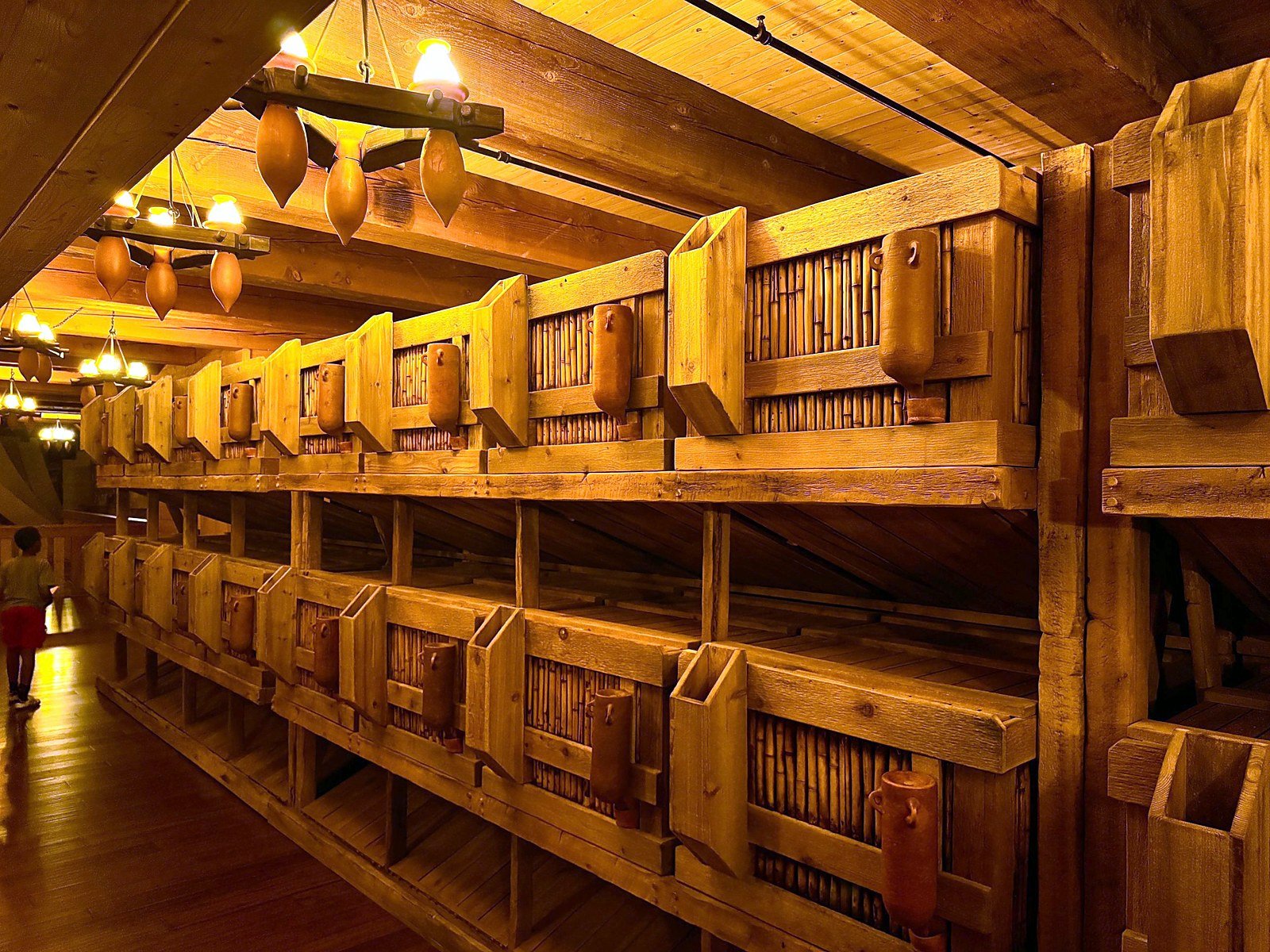 Rows of wooden animal stalls lit by hanging lanterns inside the Ark Encounter