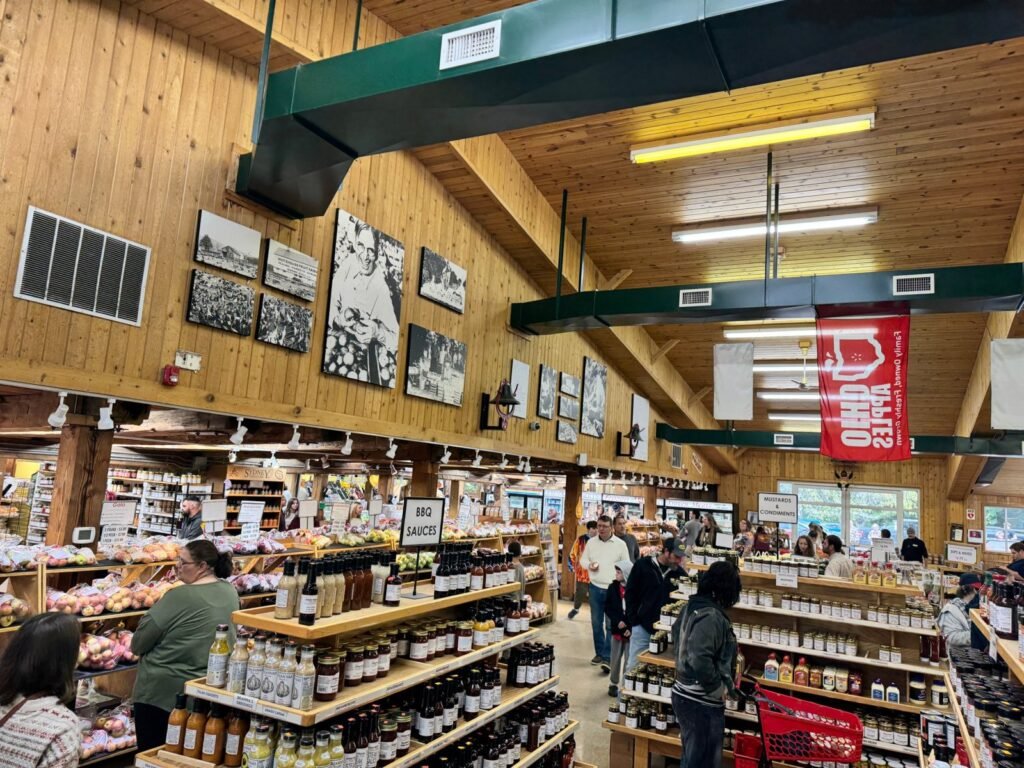 Market aisles of sauces and apples below black-and-white historic farm photos